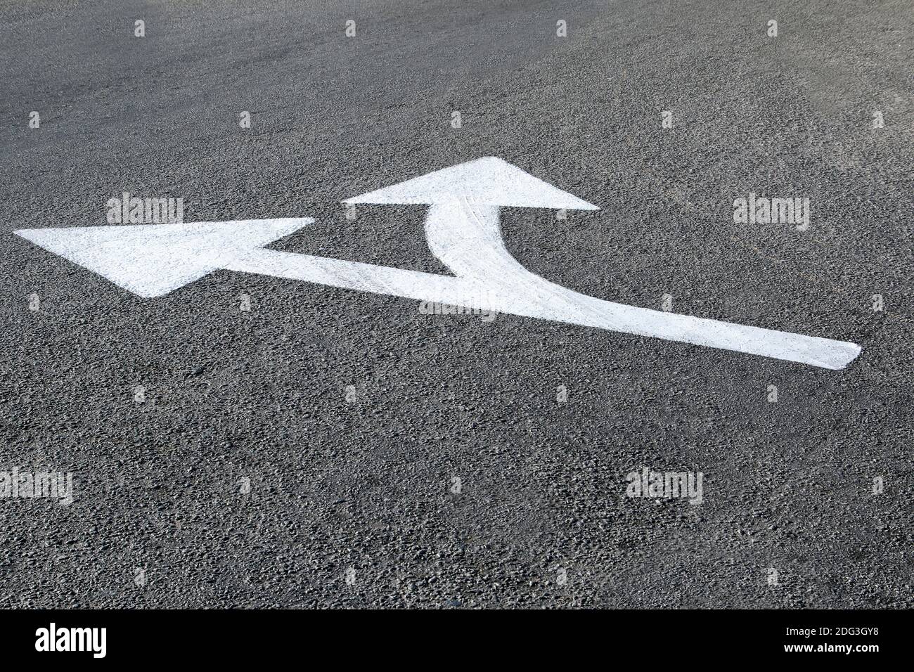 white directional arrow drawn on the asphalt ground - concept of paths and directions Stock Photo