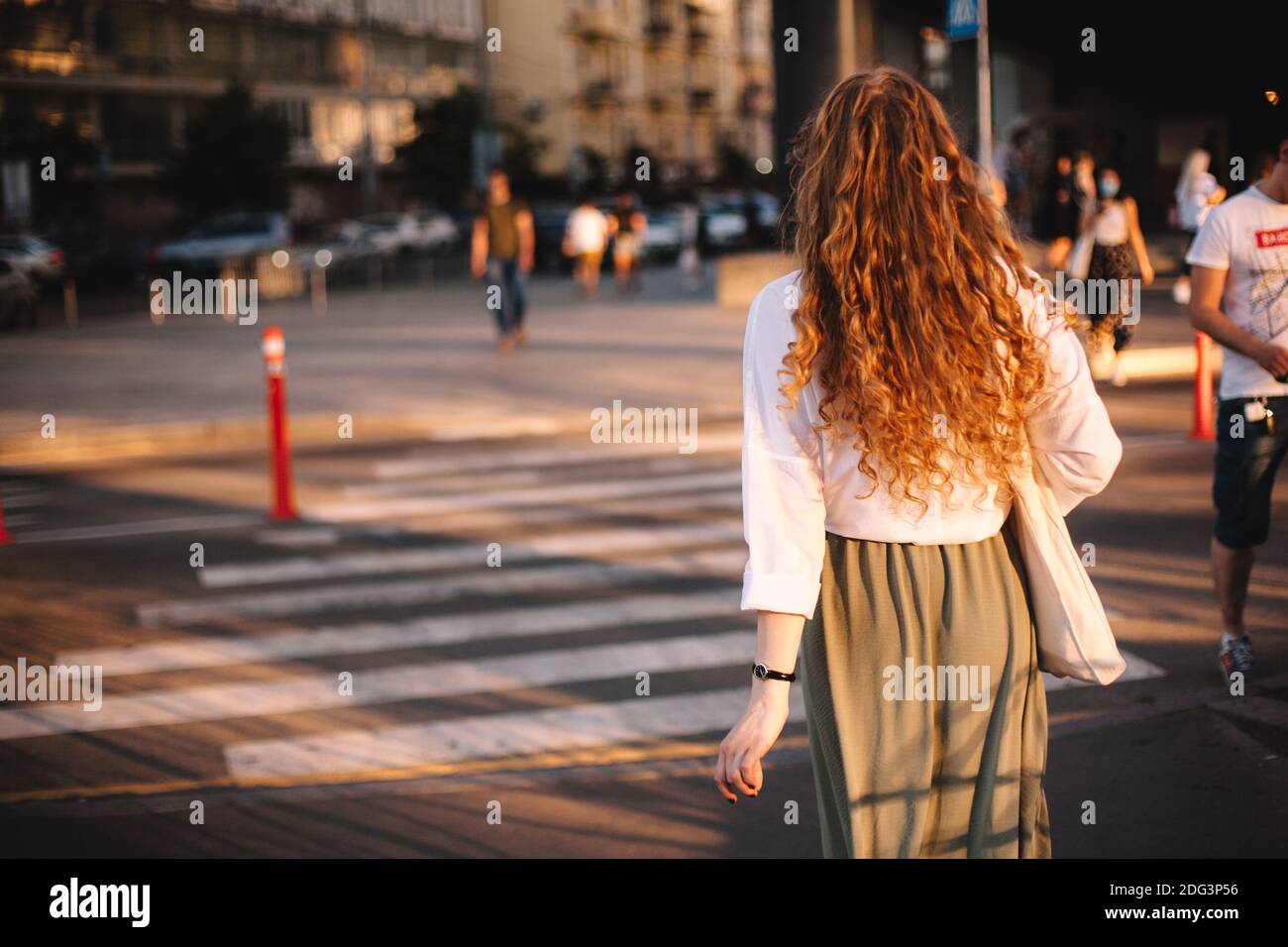 Back view of woman walking on street in city at sunset Stock Photo - Alamy