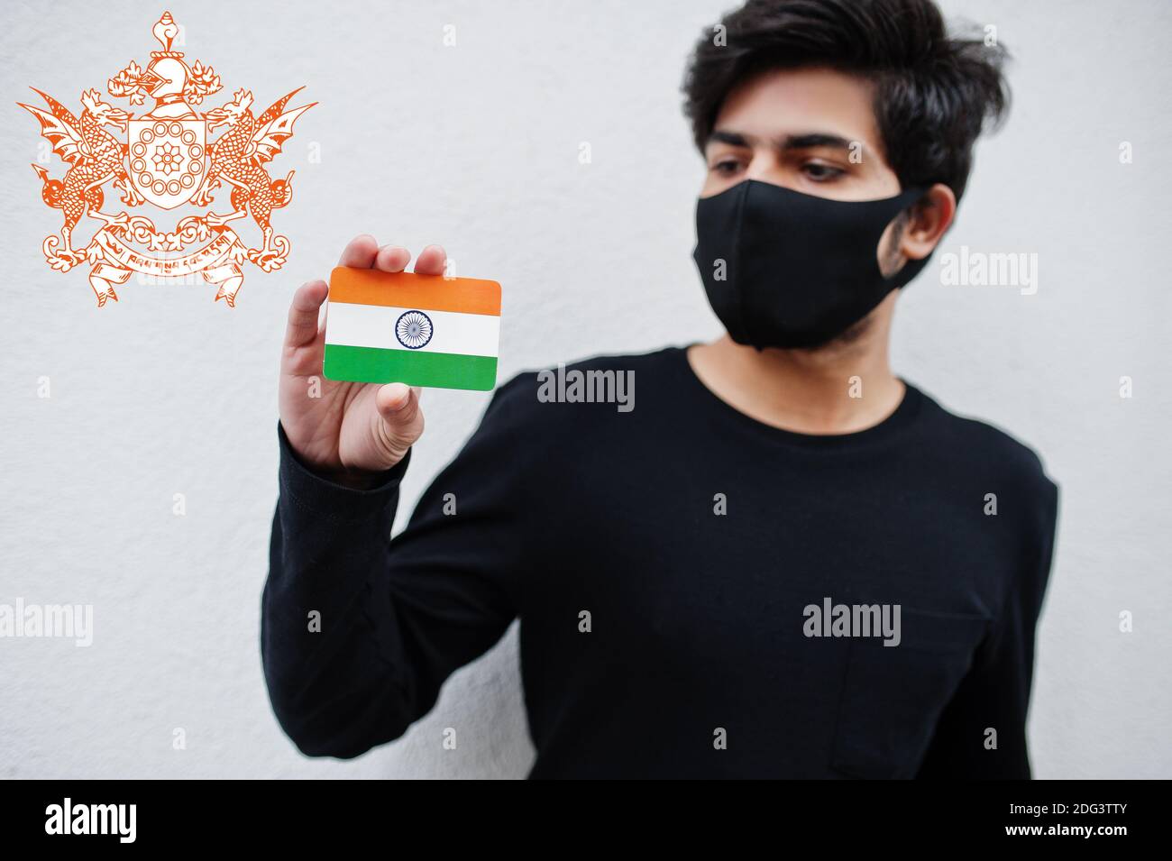 Indian man wear all black and face mask, hold India flag in hand isolated on white background with Sikkim state emblem . Coronavirus India states and Stock Photo