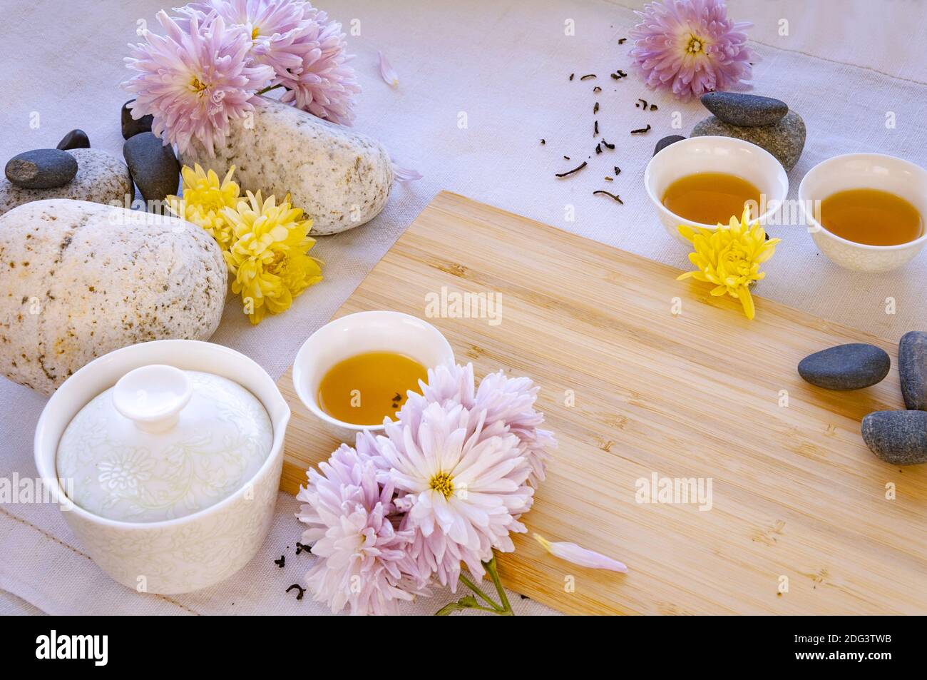 Chinese white tea cups on a bamboo board, beautiful white porcelain gaiwan zhong, flowers and stones Stock Photo