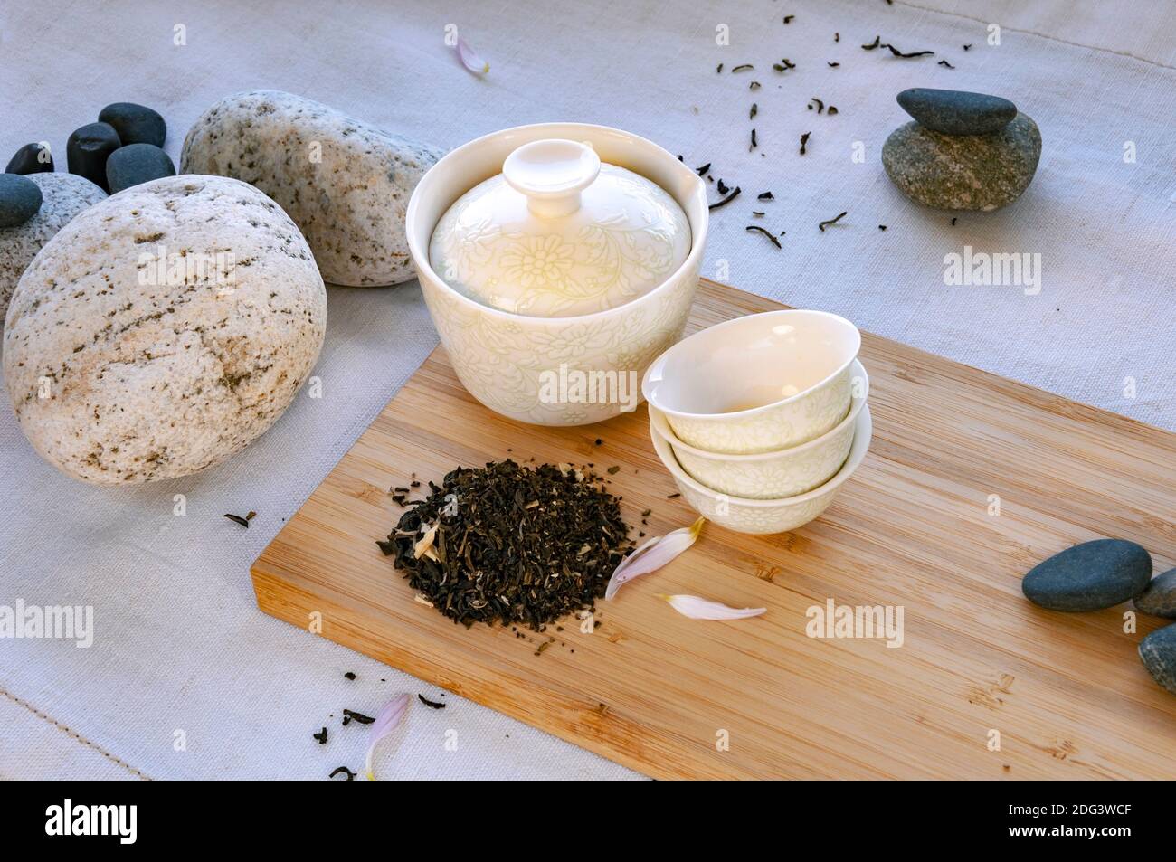 small Chinese white tea cups with black tea on a bamboo board, beautiful white porcelain gaiwan zhong. Stock Photo