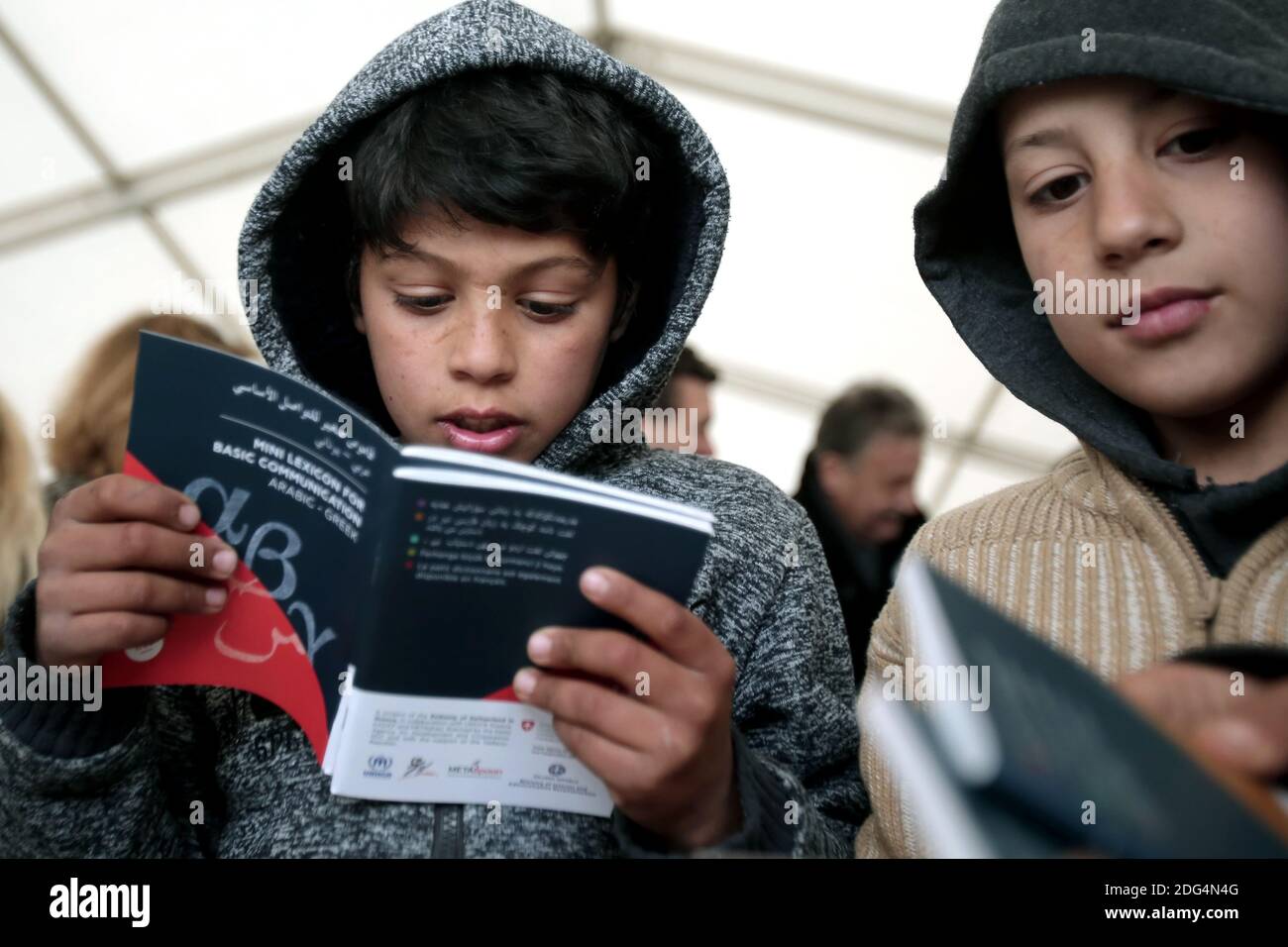 Refugee boys look at lexicons given by Greek Migration Minister and the Ambassador of Switzerland in Greece, at the Eleonas camp in Athens, Greece, on January 30, 2017. The mini lexicons, in six dialects (Arabic, Farsi, Sorani, French, Kirmantzi, Urdu) with translation in Greek and English, aim to communicate informations to migrants in Greece. Photo by Panayotis Tzamaros/ABACAPRESS.COM Stock Photo