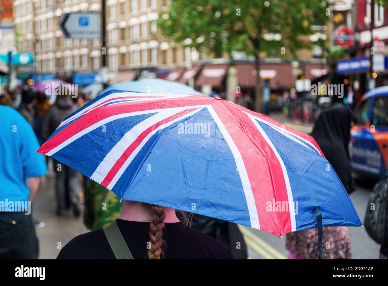 Rainy day in London with a woman wearing an umbrella with the flag of Great Britain Stock Photo