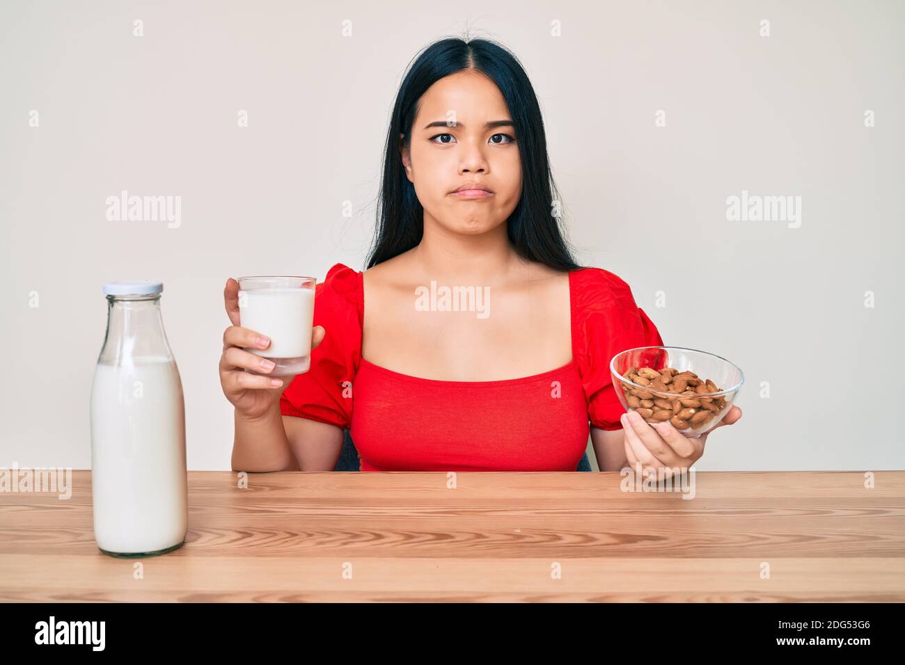 Young asian girl drinking healthy almond milk depressed and worry for distress, crying angry and afraid. sad expression. Stock Photo