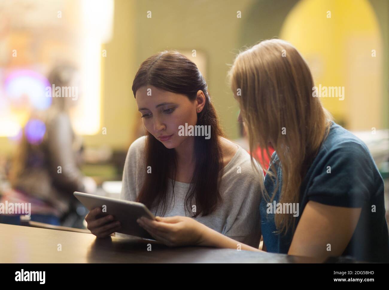 Two women in the restaurant using electronic tablet Stock Photo