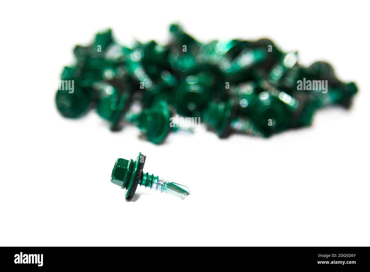 green painted screw in foreground with pile of screws out of focus