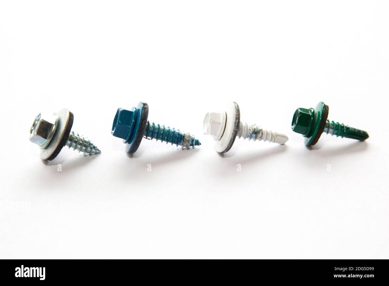 four metallic, white, blue and green colored screws on white background Stock Photo