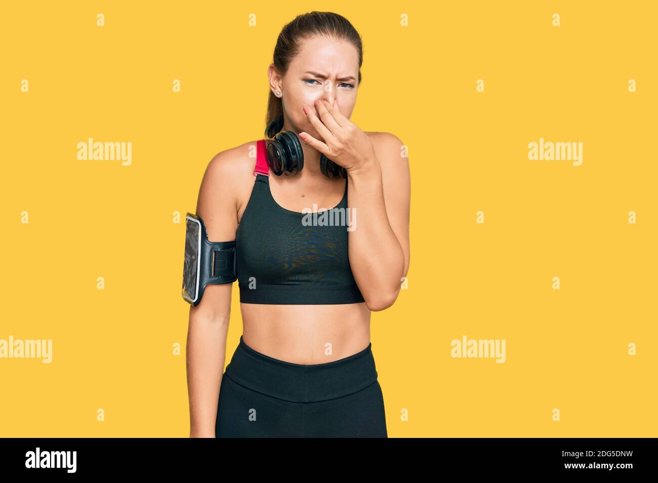 Beautiful blonde woman wearing gym clothes and using headphones