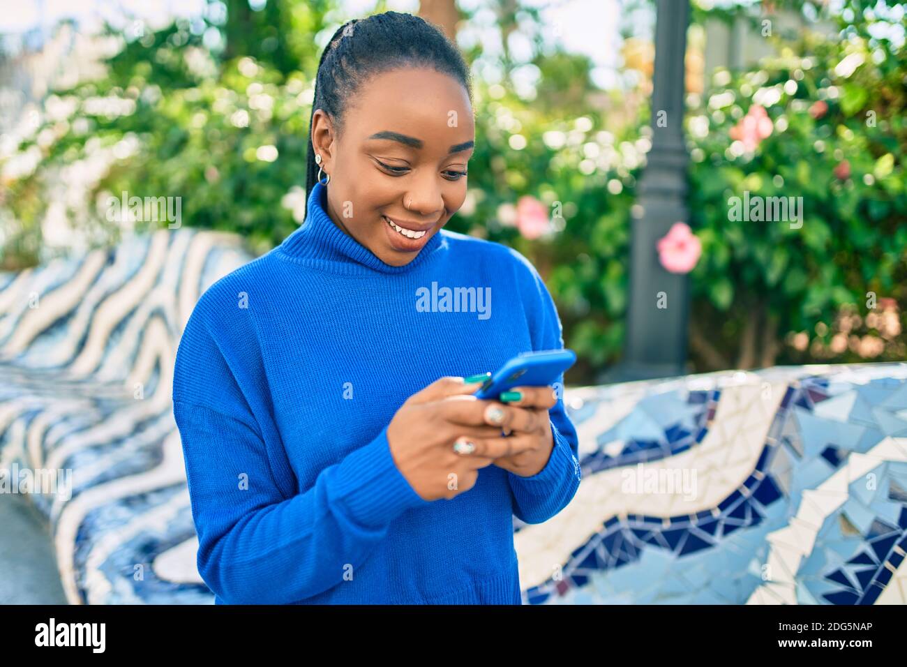 Young african american woman smiling happy using smartphone at the park ...