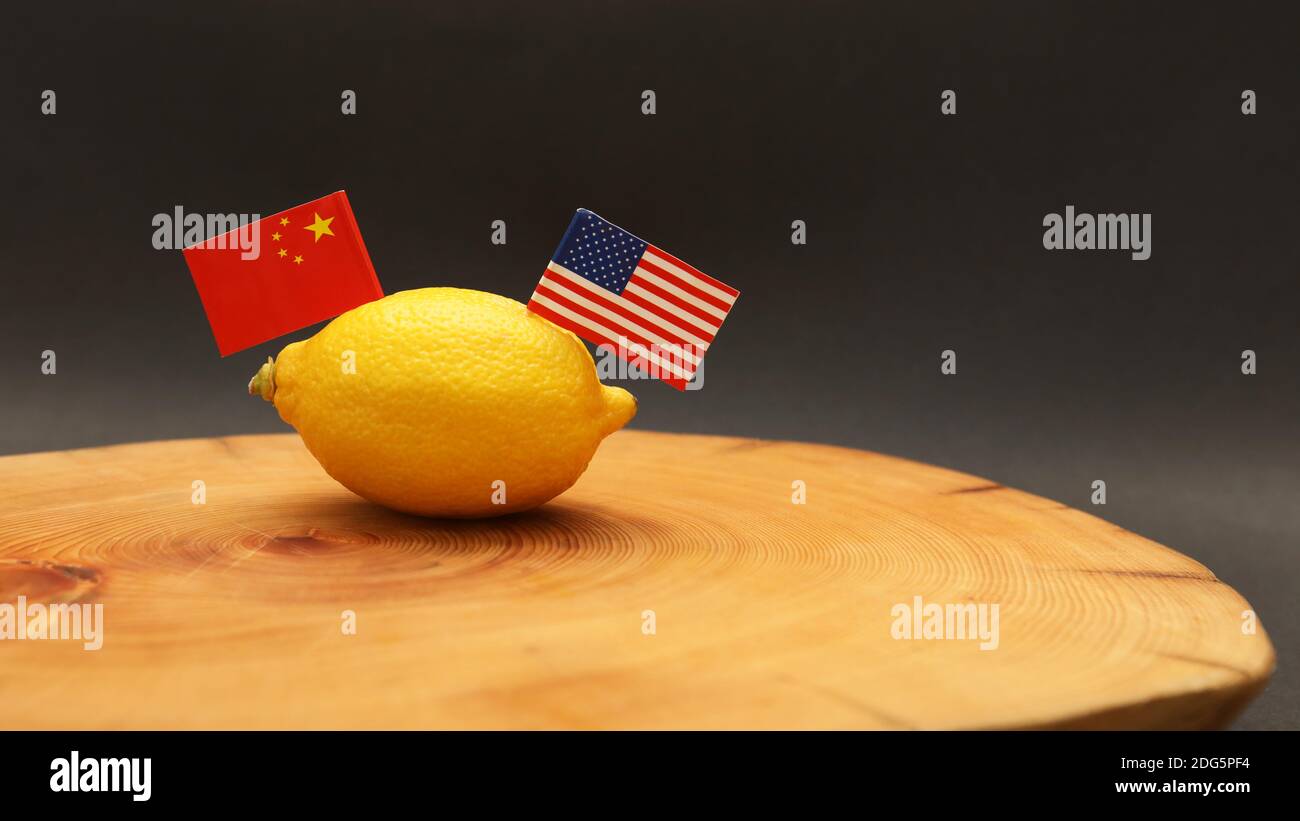 US American and Chinese flags poking out of a lemon on a chopping block representing the strained soured relationship and trade war being waged betwee Stock Photo