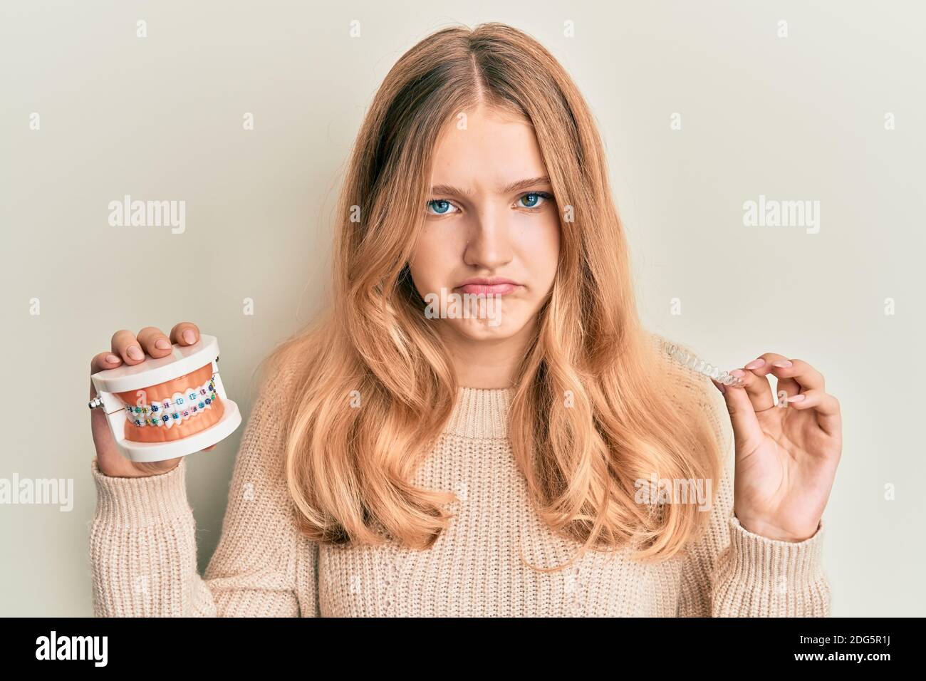 Beautiful young caucasian girl holding invisible aligner orthodontic