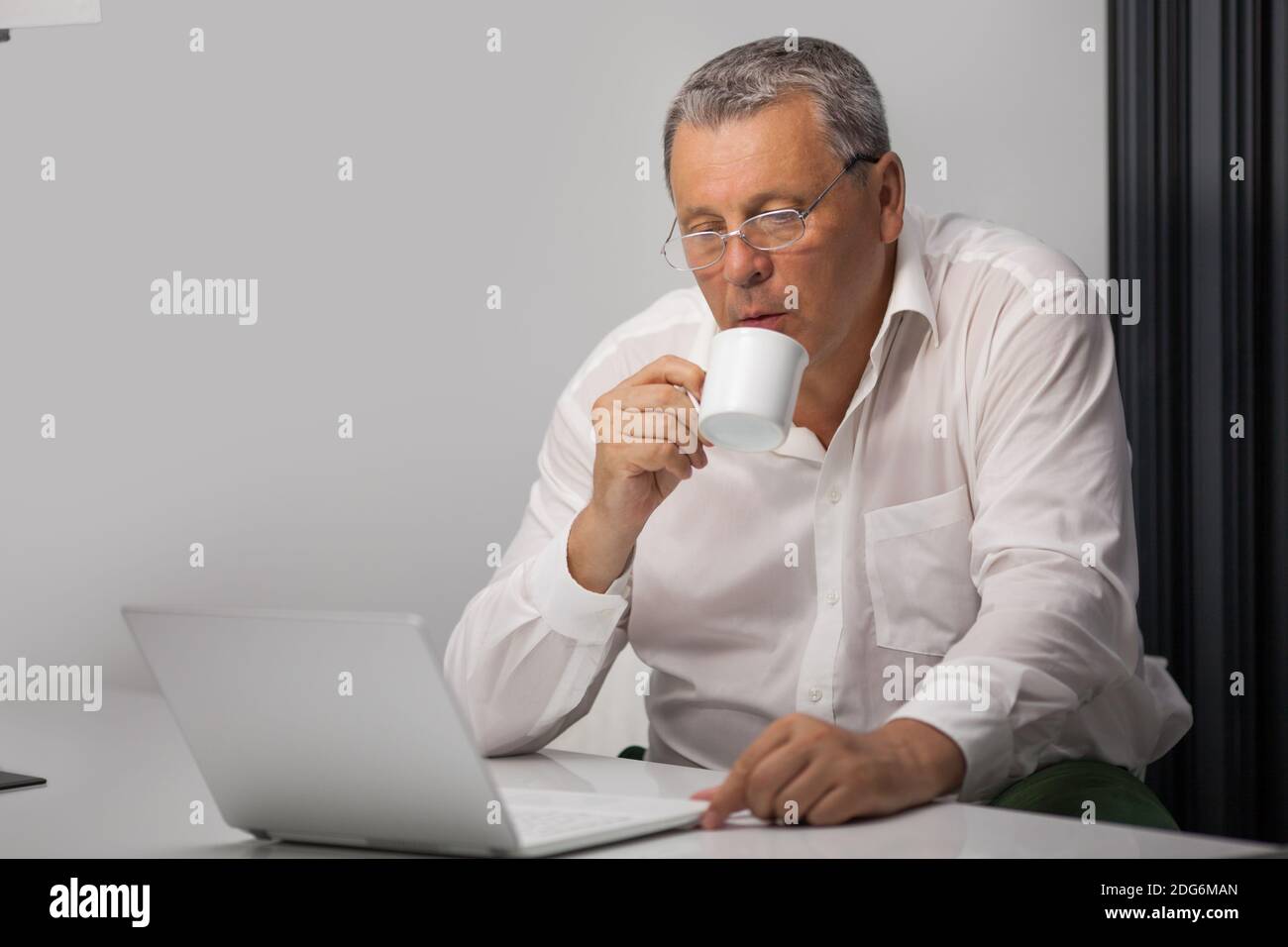 Businessman drinking coffee while working in office Stock Photo