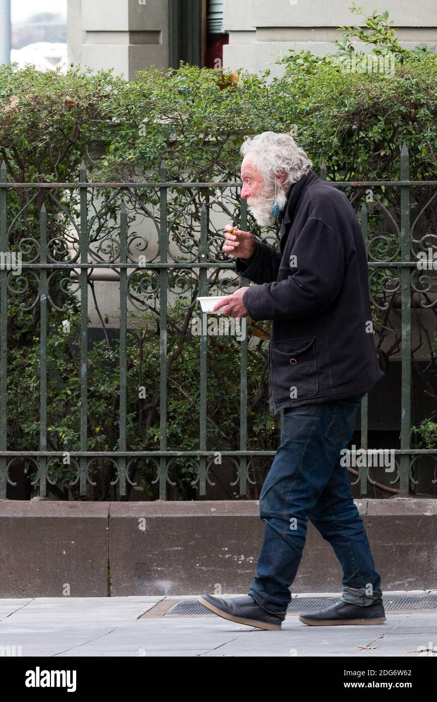 Melbourne, Australia, 24 August, 2020. One of Melbourne's homeless is seen walking by number 1 Collins Street during COVID-19 in Melbourne, Australia. Premier Daniel Andrews announced yesterday his plans to extend Victoria's State of Emergency for another 12 months giving his government and his Chief Health Officer, Brett Sutton, unprecedented powers as well as the ability to curtail democratic checks and balances. It comes as case numbers continue to fall. Responsibility for the current wave the State is experiencing rests solely on the Andrews Governments shoulders and some are saying that Stock Photo