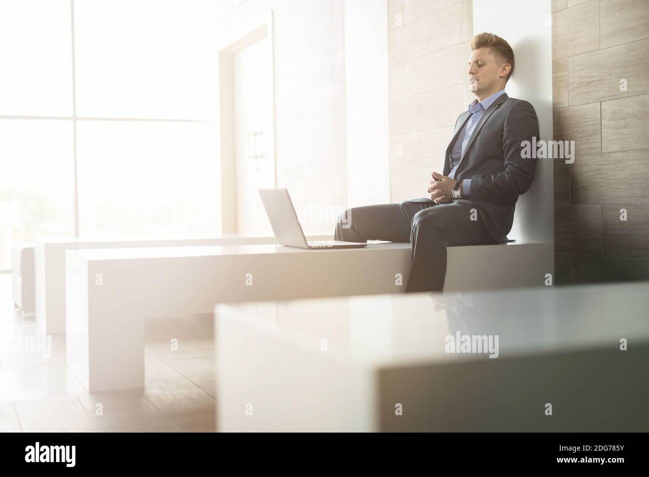 Business man sitting alone on a bench with laptop Stock Photo