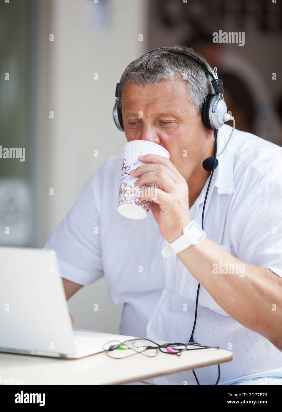 Man Drinking Coffee and Using Laptop at Cafe Stock Photo