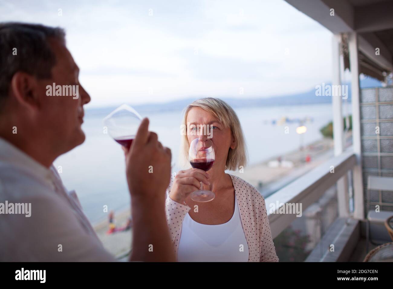 Couple Drinking Red Wine on Balcony of Beach Hotel Stock Photo - Alamy