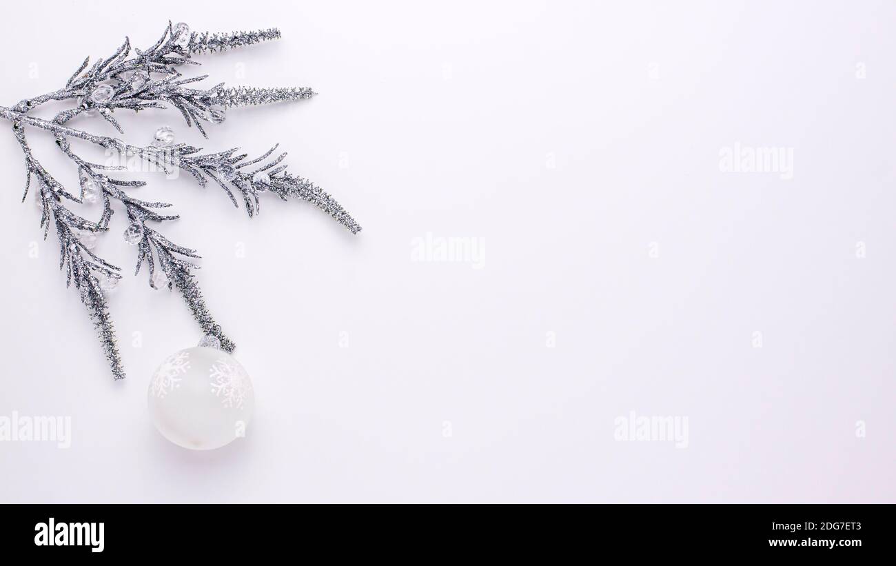 Silver artificial shine Christmas branch with white ball swinging back and forth isolated on white background from above. Flat lay holidays with copy Stock Photo