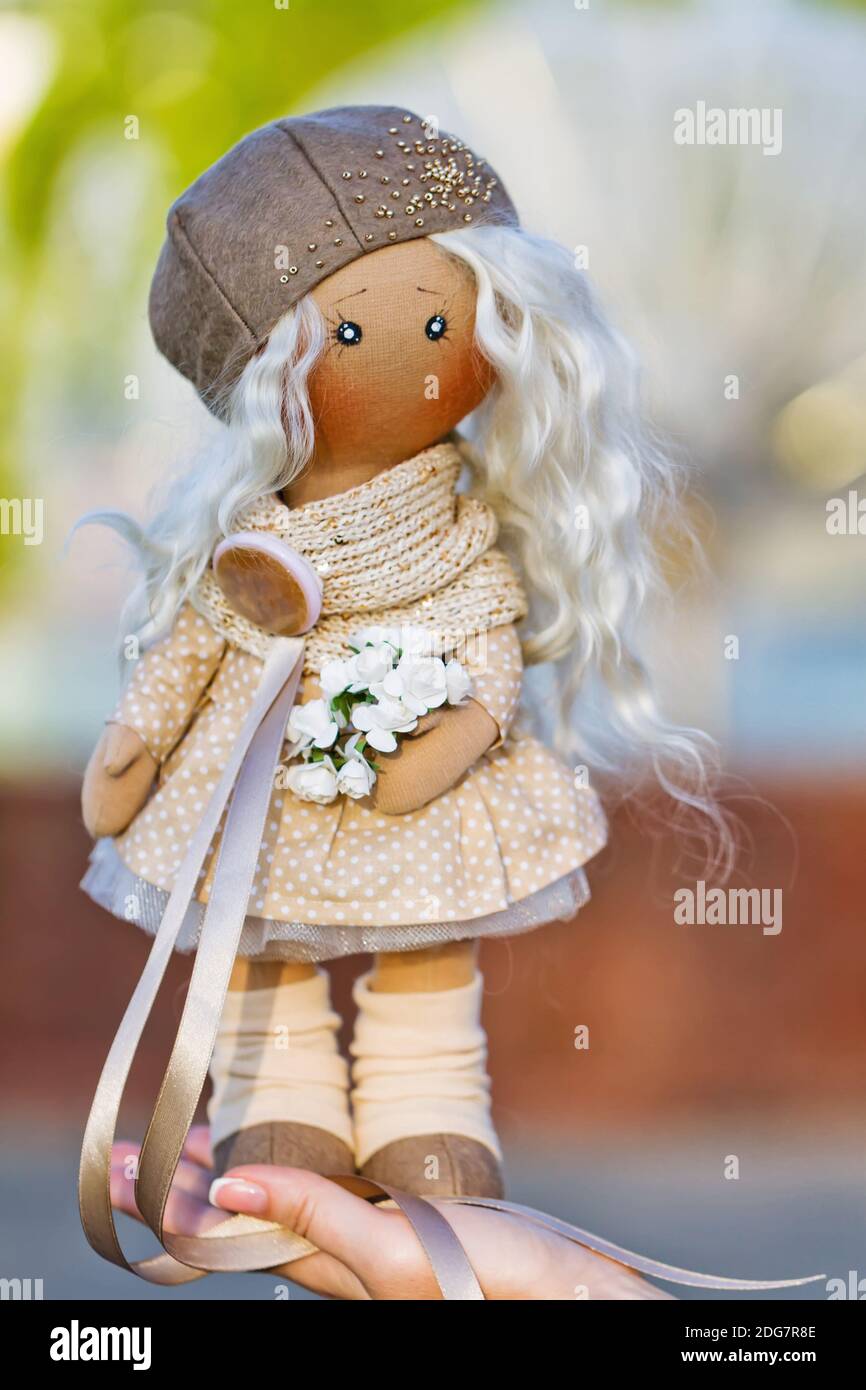 Textile doll with real hair dressed in a beige dress and a beret Stock Photo