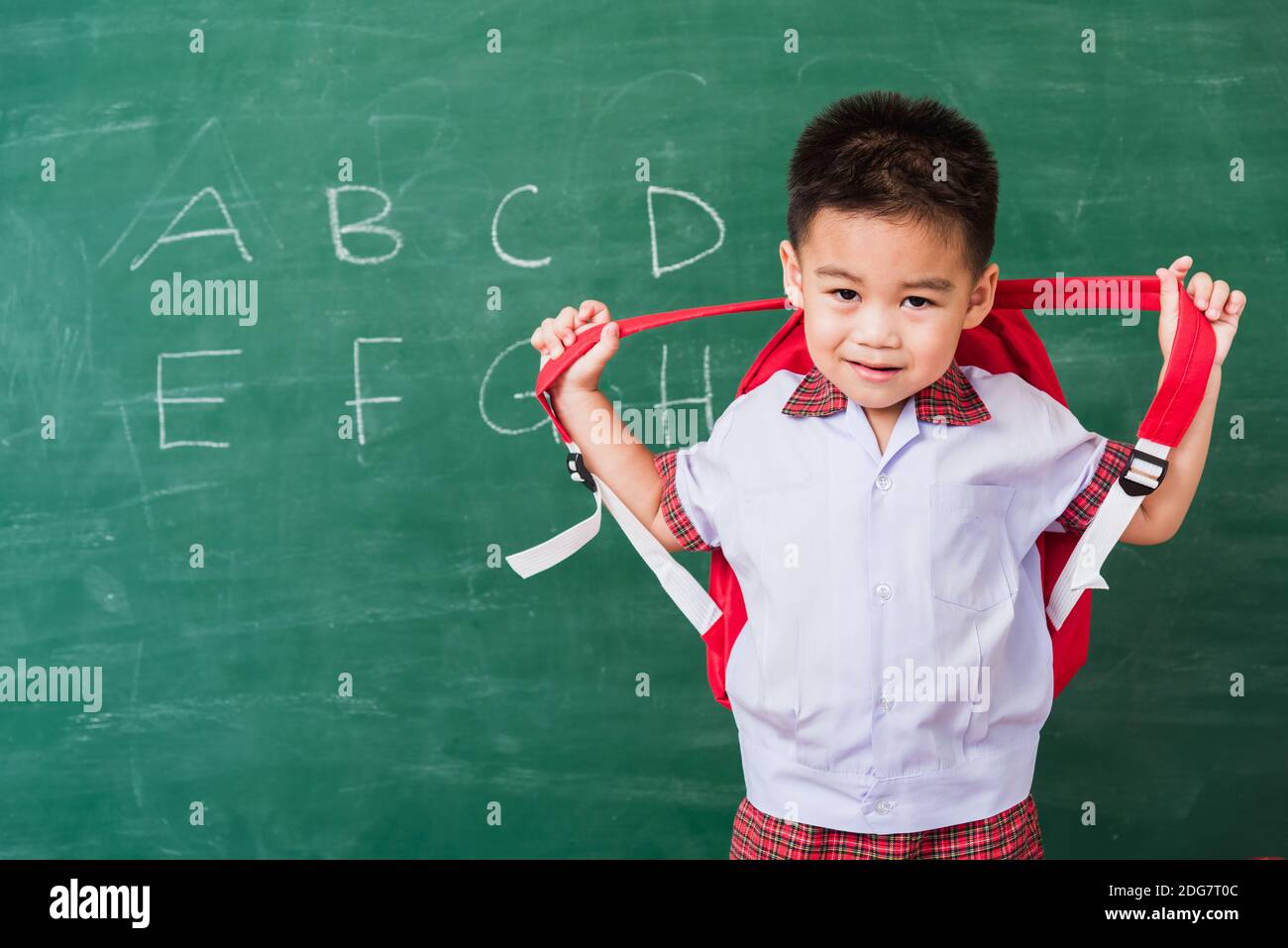https://c8.alamy.com/comp/2DG7T0C/back-to-school-happy-asian-funny-cute-little-child-boy-kindergarten-preschool-in-student-uniform-wearing-school-bag-stand-smiling-on-green-school-bla-2DG7T0C.jpg