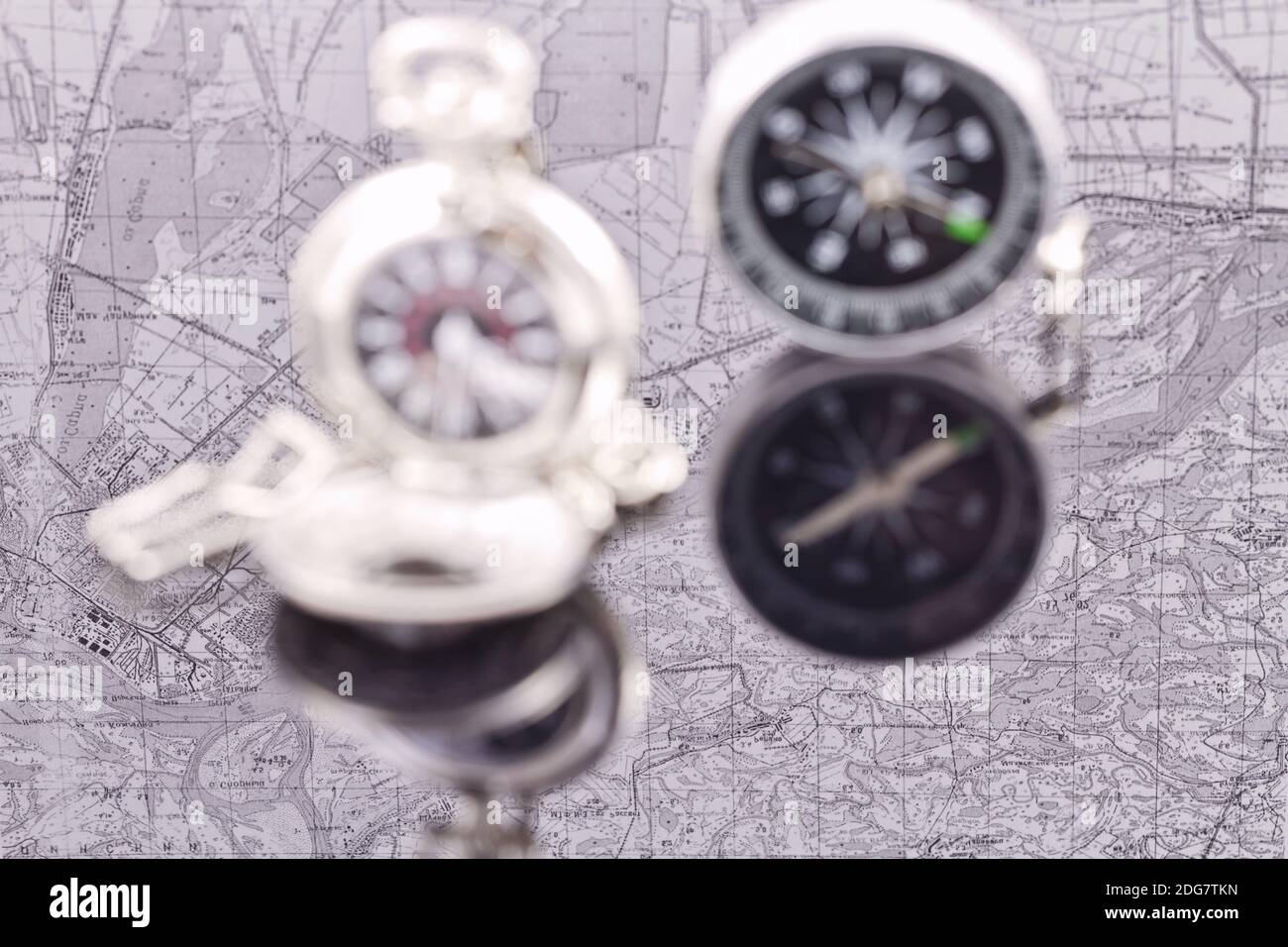 Compass and a silver pocket watch on the background reflection maps Stock Photo