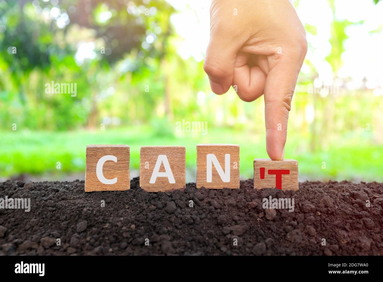 Hand changing word can't to can wooden blocks in natural background at sunrise. Positivity, yes you can, business success, motivation, achievement. Stock Photo