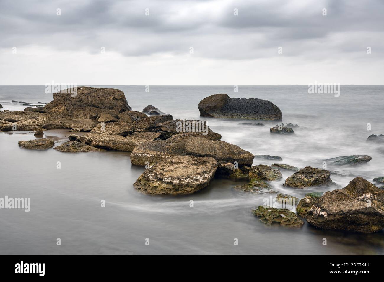 Rocky sea beach at cloudy weather, Long exposure photo Stock Photo - Alamy