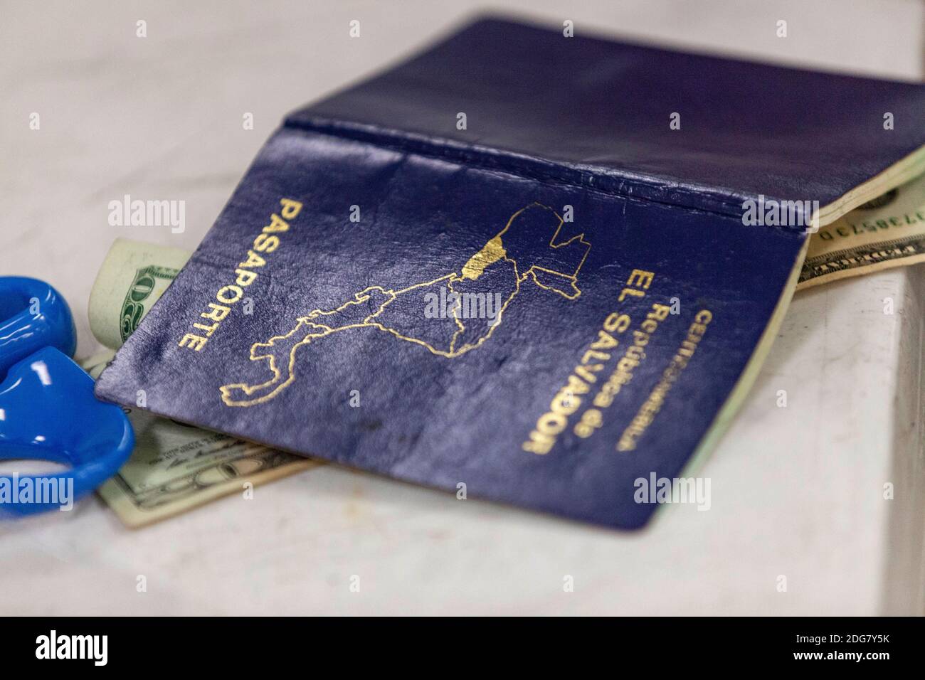 El Salvadoran passport on a table with money for the new issue. New  Passports cost $60, a second issue of a person's passport costs $80 and a  third issue or more is