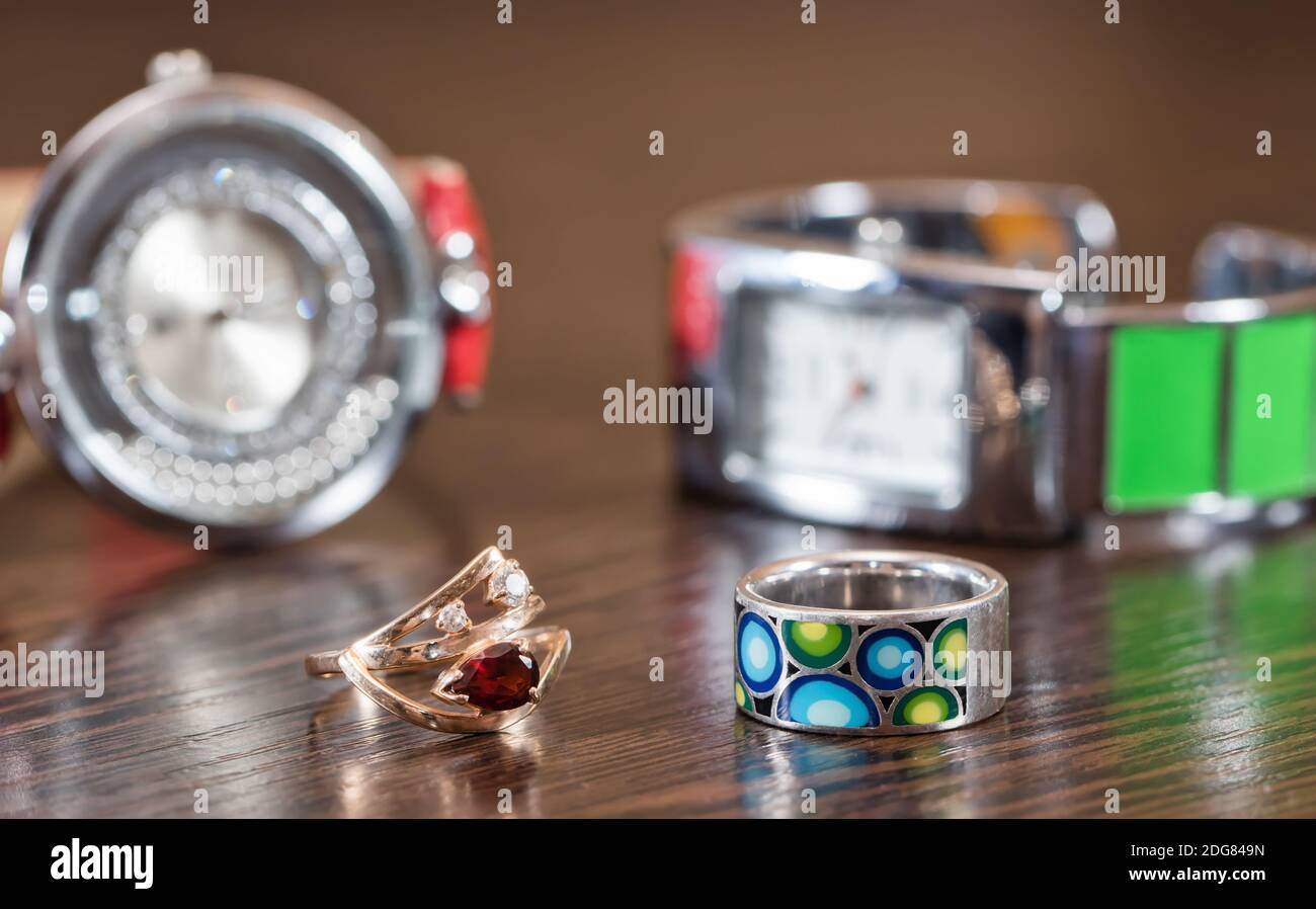 Multi-colored silver ring and a gold ring with a ruby on a background of watches Stock Photo