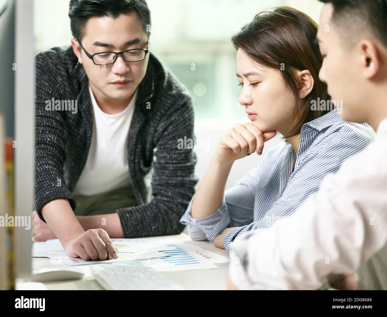 team of asian men and woman discussing business in office Stock Photo