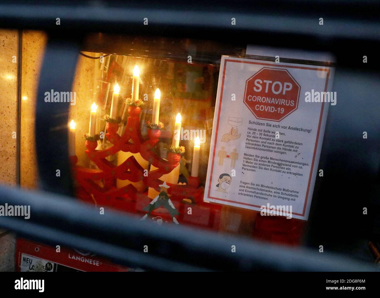 Cologne Germany 08th Dec 2020 The Electric Candles Of A Christmas Tree Burn Behind A Rolling Door Of A Shop On Which A Sign With Corona Warnings Is Stuck Strict Rules Apply