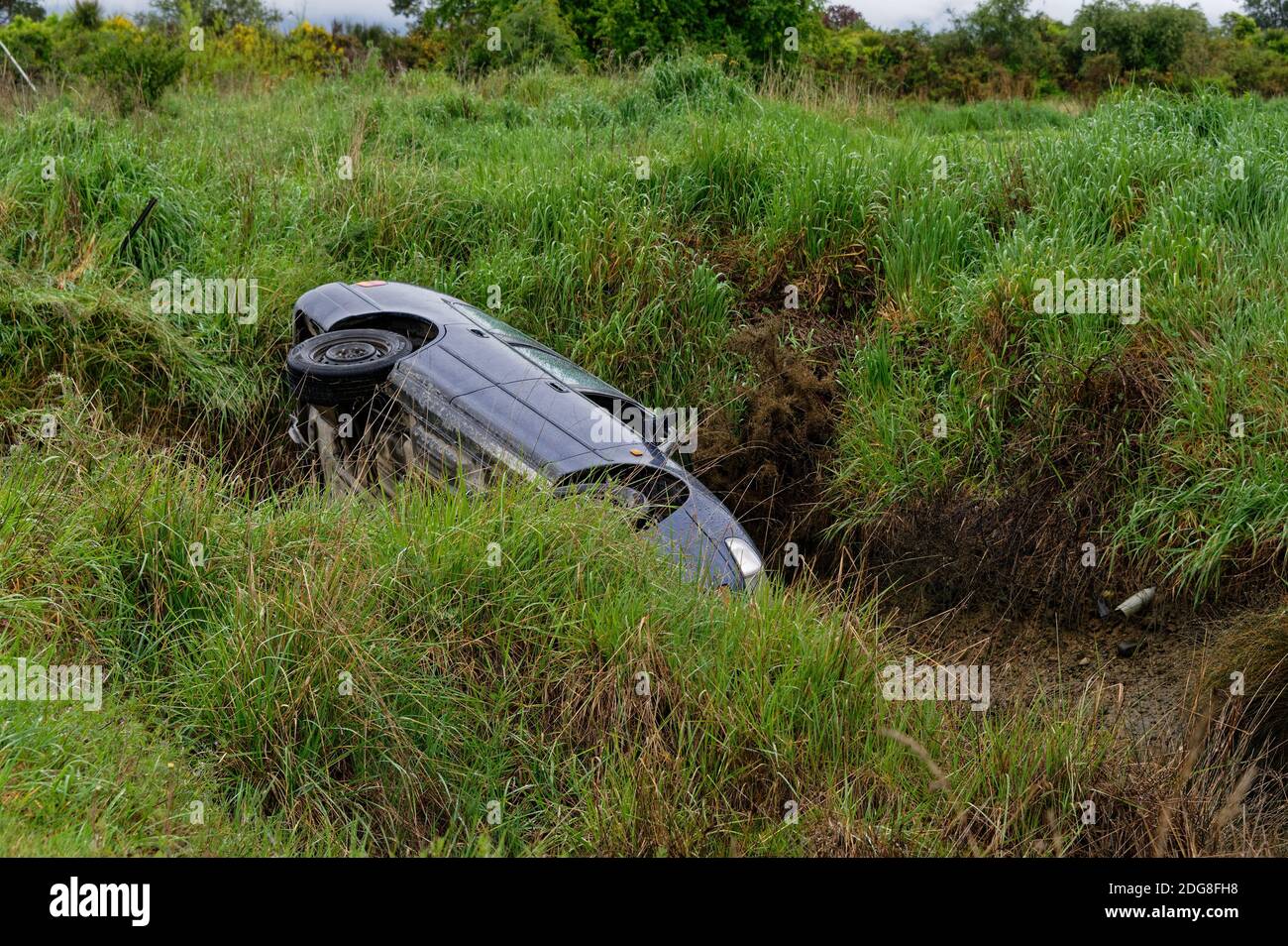 A driving has not been cautious and has lost control of his car, ending up over a bank Stock Photo