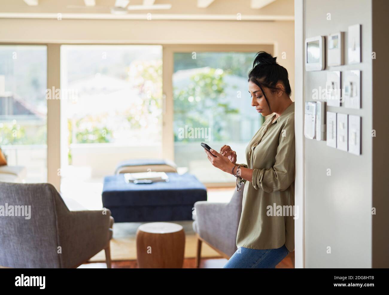 Woman using smart phone by home automation controls Stock Photo