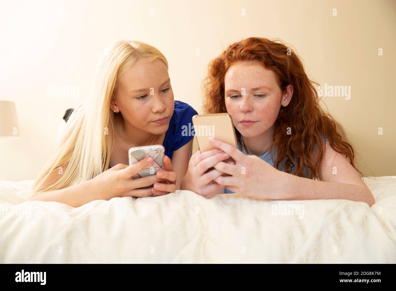 Preteen girl friends using smart phones on bed Stock Photo
