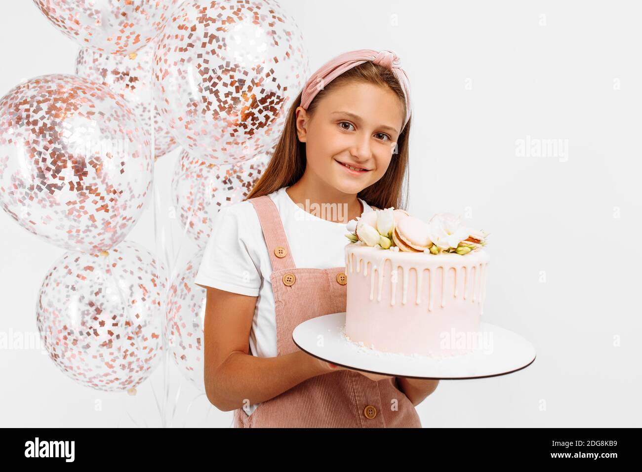 Beautiful happy little girl holding a beautiful big birthday cake