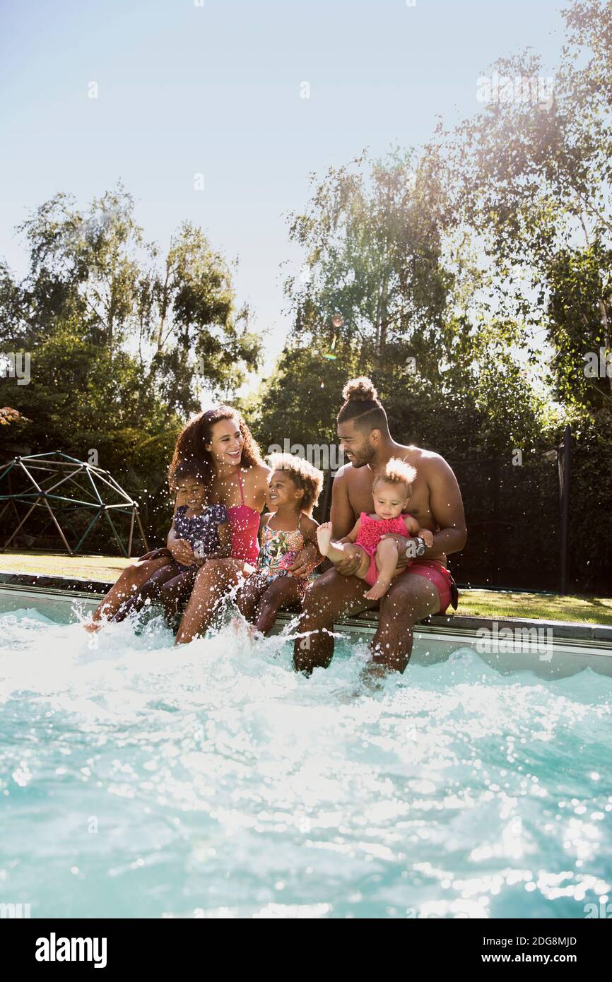 Happy family splashing at sunny summer poolside Stock Photo - Alamy