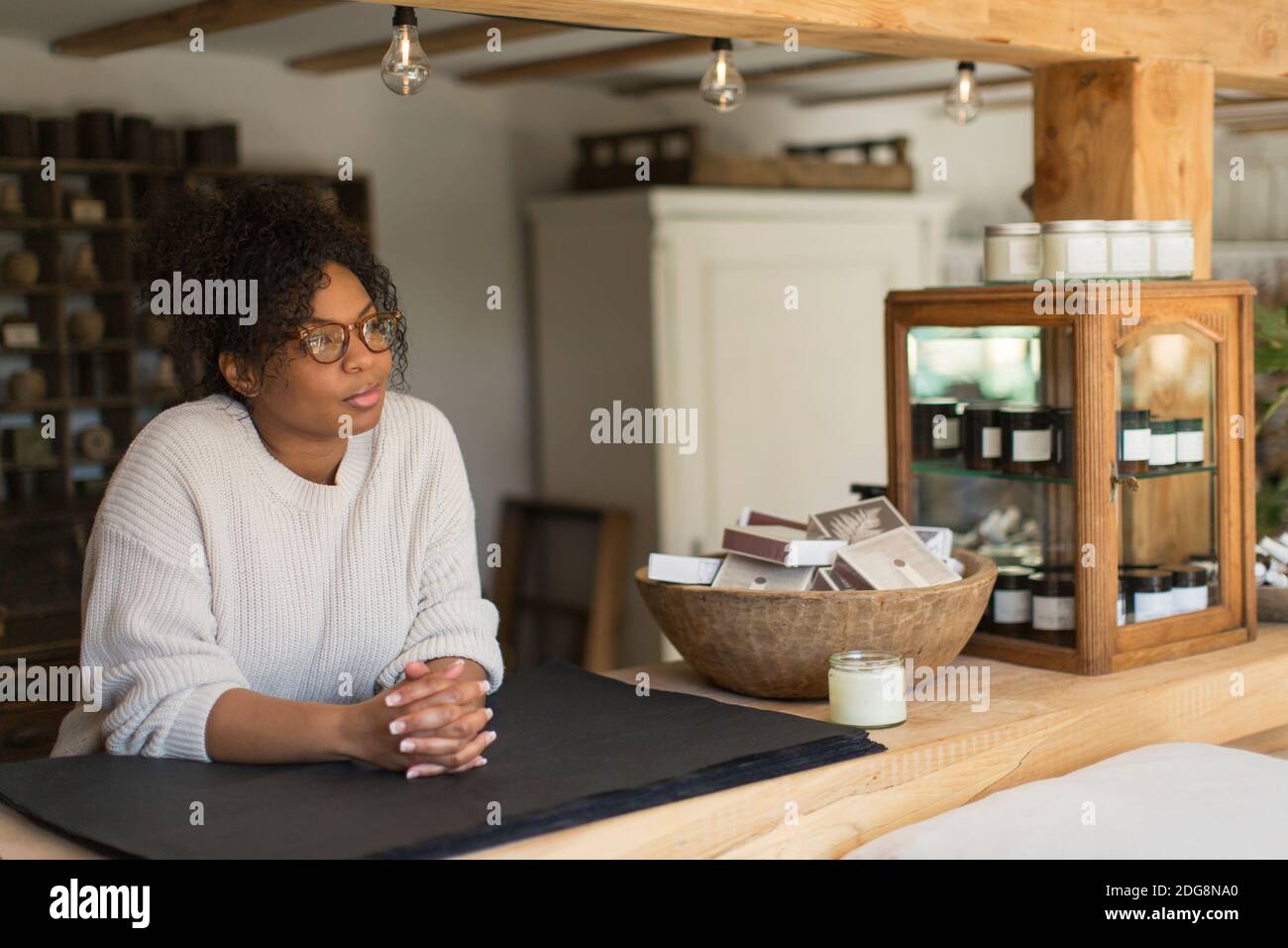 Thoughtful female shop owner behind counter Stock Photo