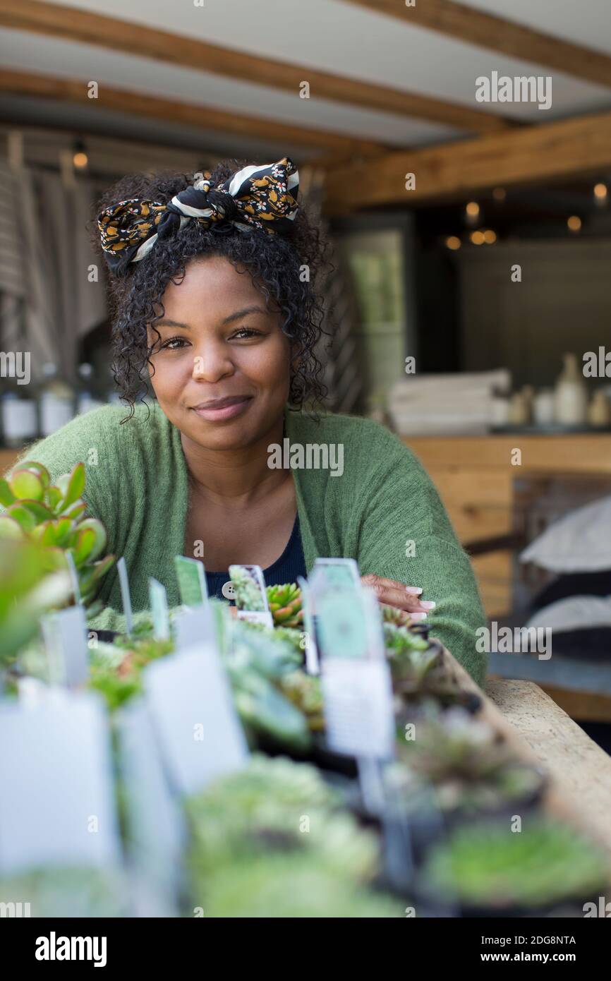 Portrait female shop owner at succulent display in plant nursery Stock Photo