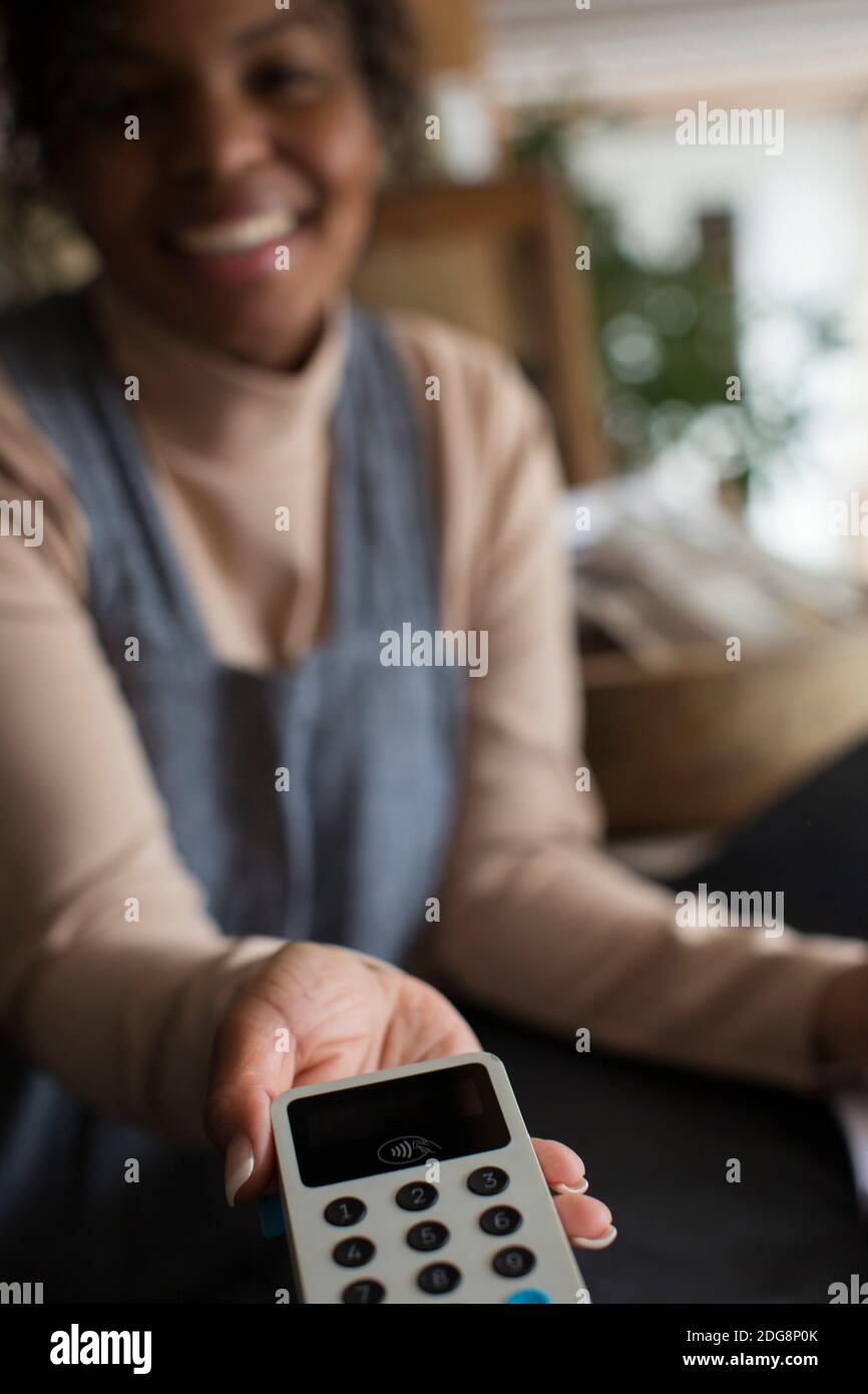 POV female shop owner holding credit card reader for customer Stock Photo