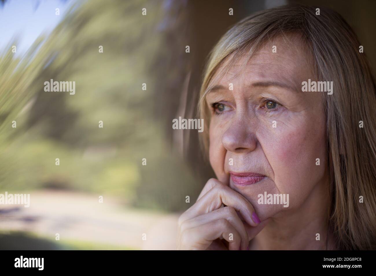 Close up worried senior woman looking out window Stock Photo