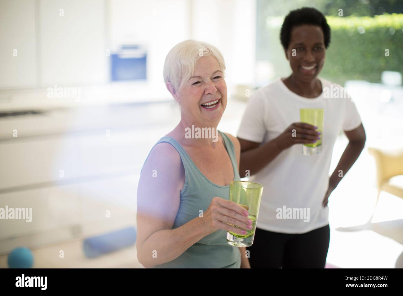 Happy senior women friends drinking water after workout at home Stock Photo