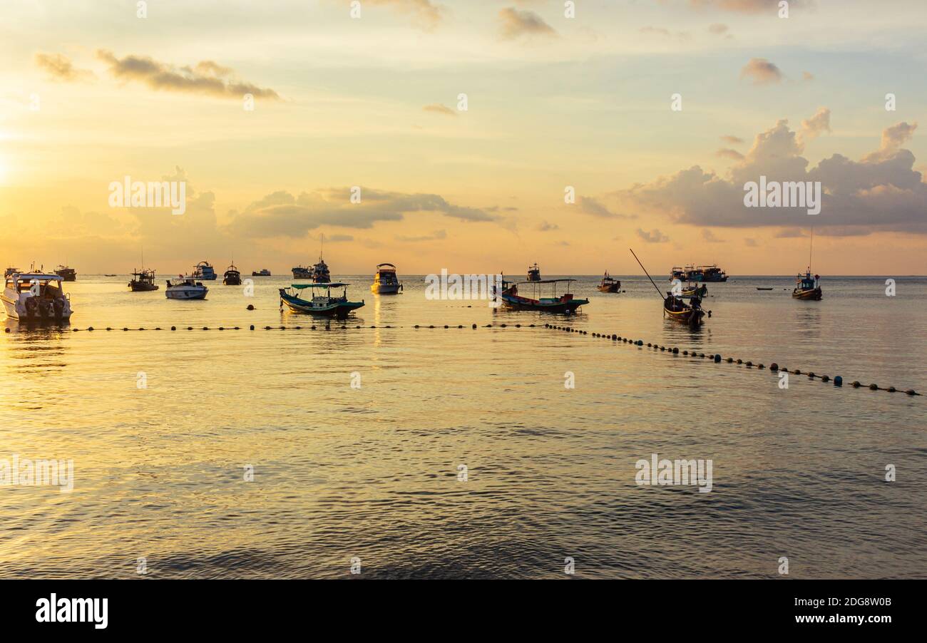 Koh Tao, Thailand: April 23 2019: island village boat pier, evening sunset time at beach, long tail boats in sea waiting for sun going down Stock Photo