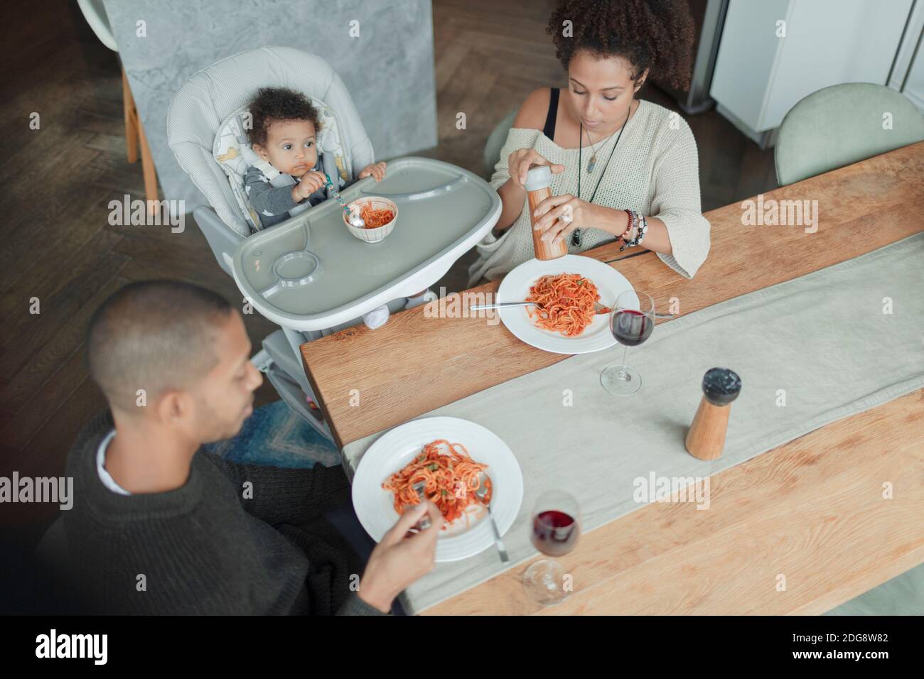 Family eating spaghetti at dining table and high chair Stock Photo