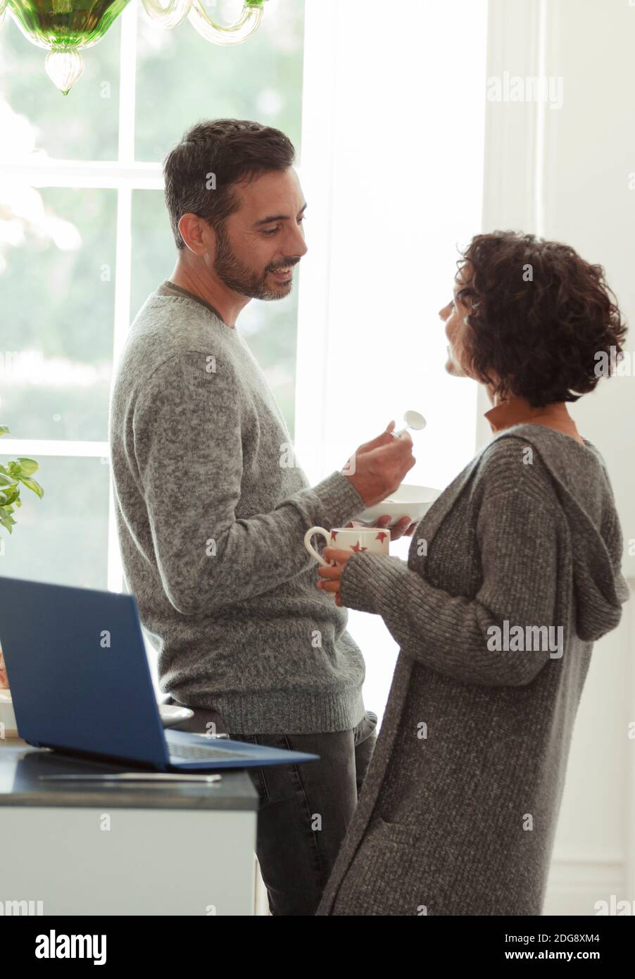 Happy couple talking and working from home in kitchen Stock Photo