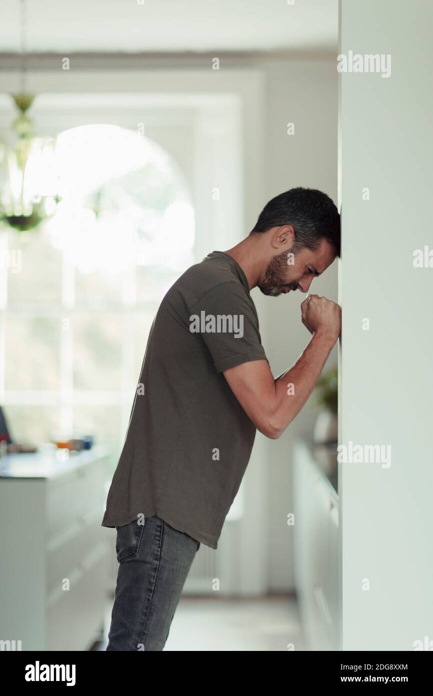 Frustrated man with clenched fists leaning against wall Stock Photo