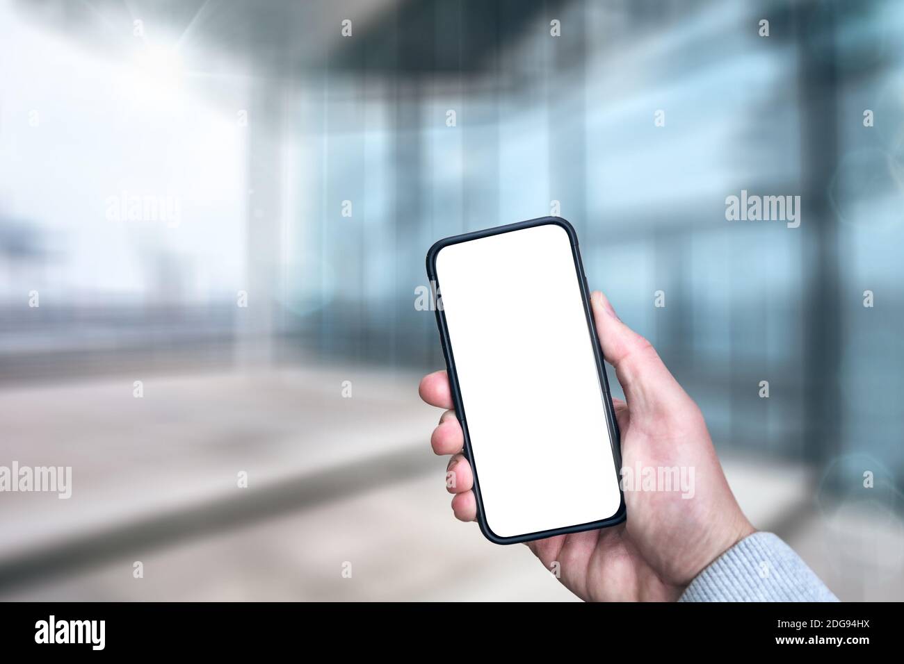 Hand holding modern smartphone with white screen Stock Photo