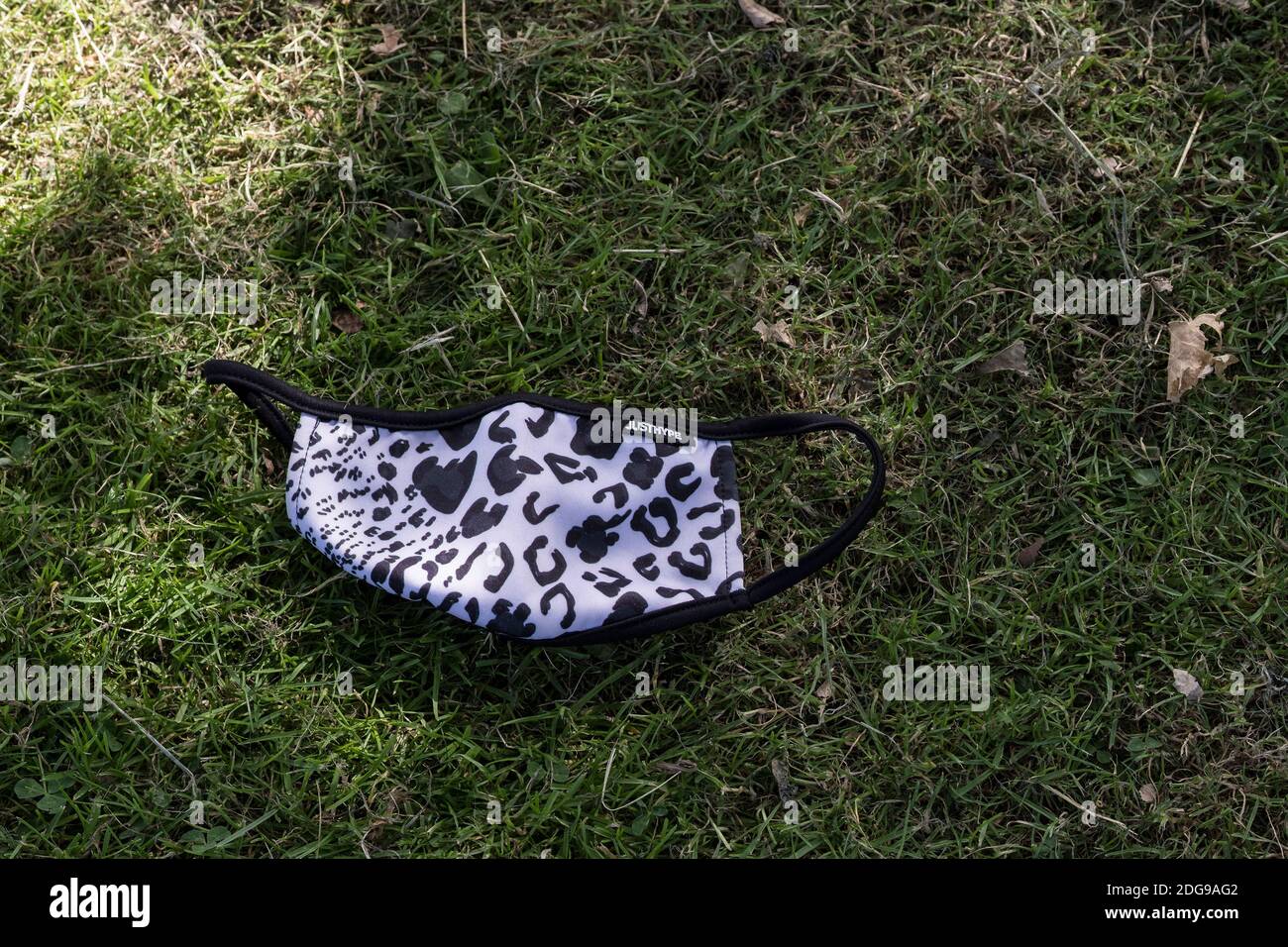 A Justhype adult animal print face mask dropped on the grass. Stock Photo