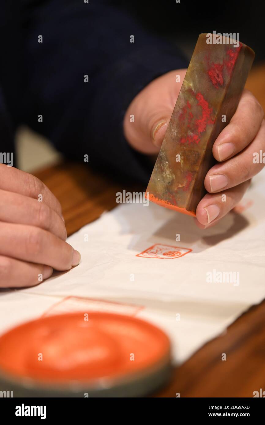 (201208) -- HANGZHOU, Dec. 8, 2020 (Xinhua) -- Jiang Sihai, vice president of the Changhua stone industry association, demonstrates a seal made of Jixue stone at a seal culture experience museum in Changhua Town, Lin'an District of Hangzhou City, east China's Zhejiang Province, Nov. 6, 2020. The Jixue stone, featuring chicken-blood bright red traces, a local specialty in Changhua Town of Hangzhou City, is a highly sought-after material for making seals and carving handicrafts. Inspired by its colors, artisan have been bringing ingeniously-designed and broadly-themed creations throughout its lo Stock Photo