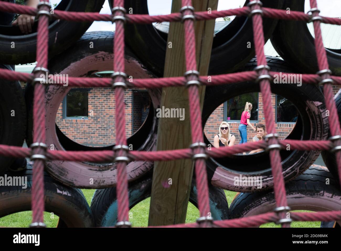 Knottingley, UK – 04 Aug 2017 – Parents watch children play on the tyre climbing frame at The Addy, The Old Quarry Adventure Playground at Warwick Est Stock Photo