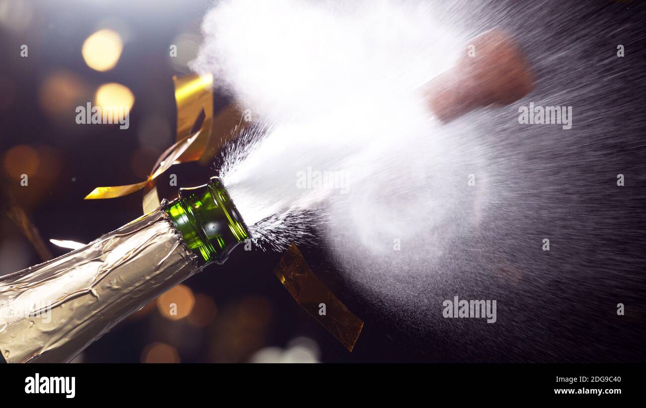 Detail of champagne wine splashing from bottle with neon lights. Celebration and holiday theme. Stock Photo