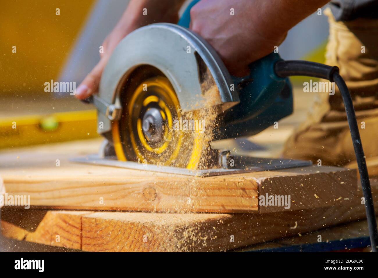 Carpenter using circular saw for cutting wooden boards with hand power tools. Stock Photo
